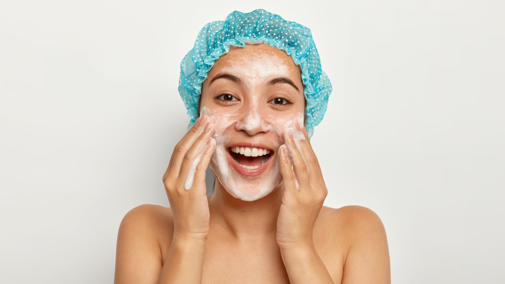 A young, attractive model touches her cheeks while doing a double cleansing.