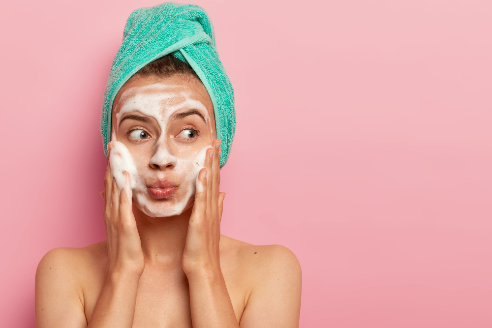 A young, attractive woman uses a face cleanser to wash her face.