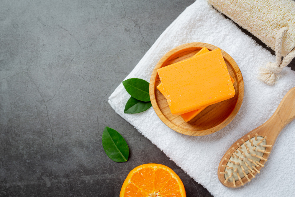 Kojic acid soap with fresh orange on a dark background.