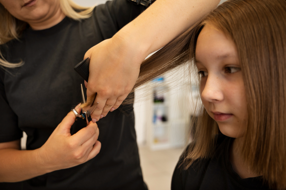 Girl getting step haircut at salon side view.