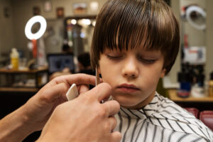 Front view hairdresser holding comb and doing bob cut.