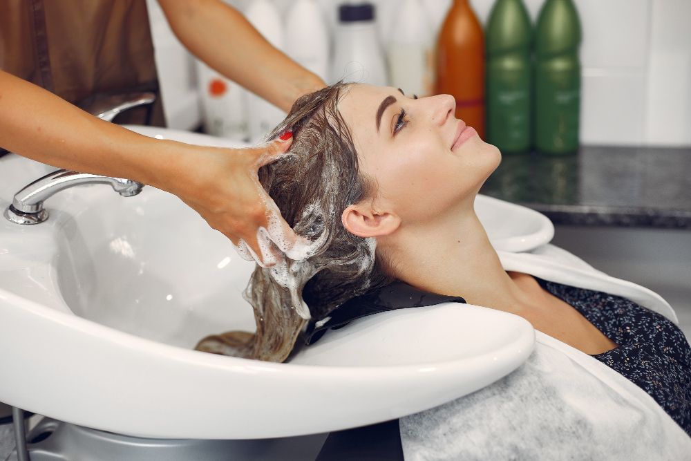 Woman washing her hair at a salon with shampoo.